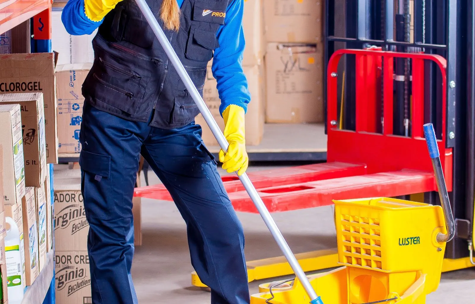 Uniformed janitor with commercial cleaning cart in office hallway